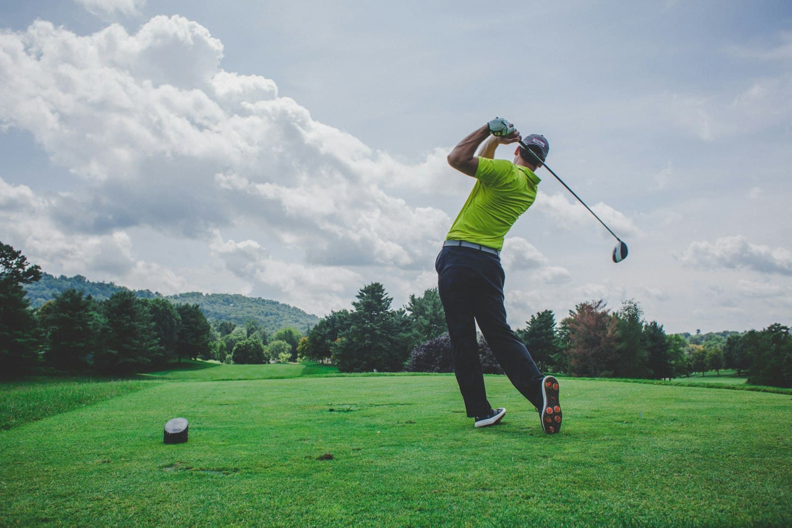 Golfer teeing off with forested Blue Ridge hills beyond